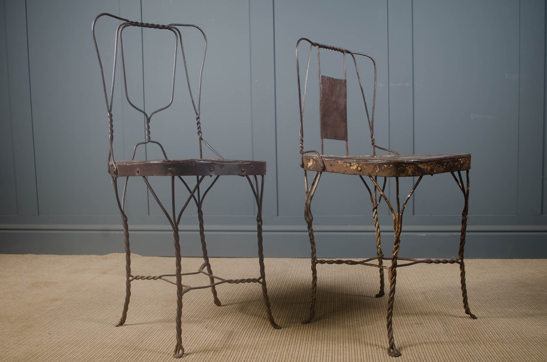 Two wrought iron chairs against a gray wall. reclaimed indian wire chairs