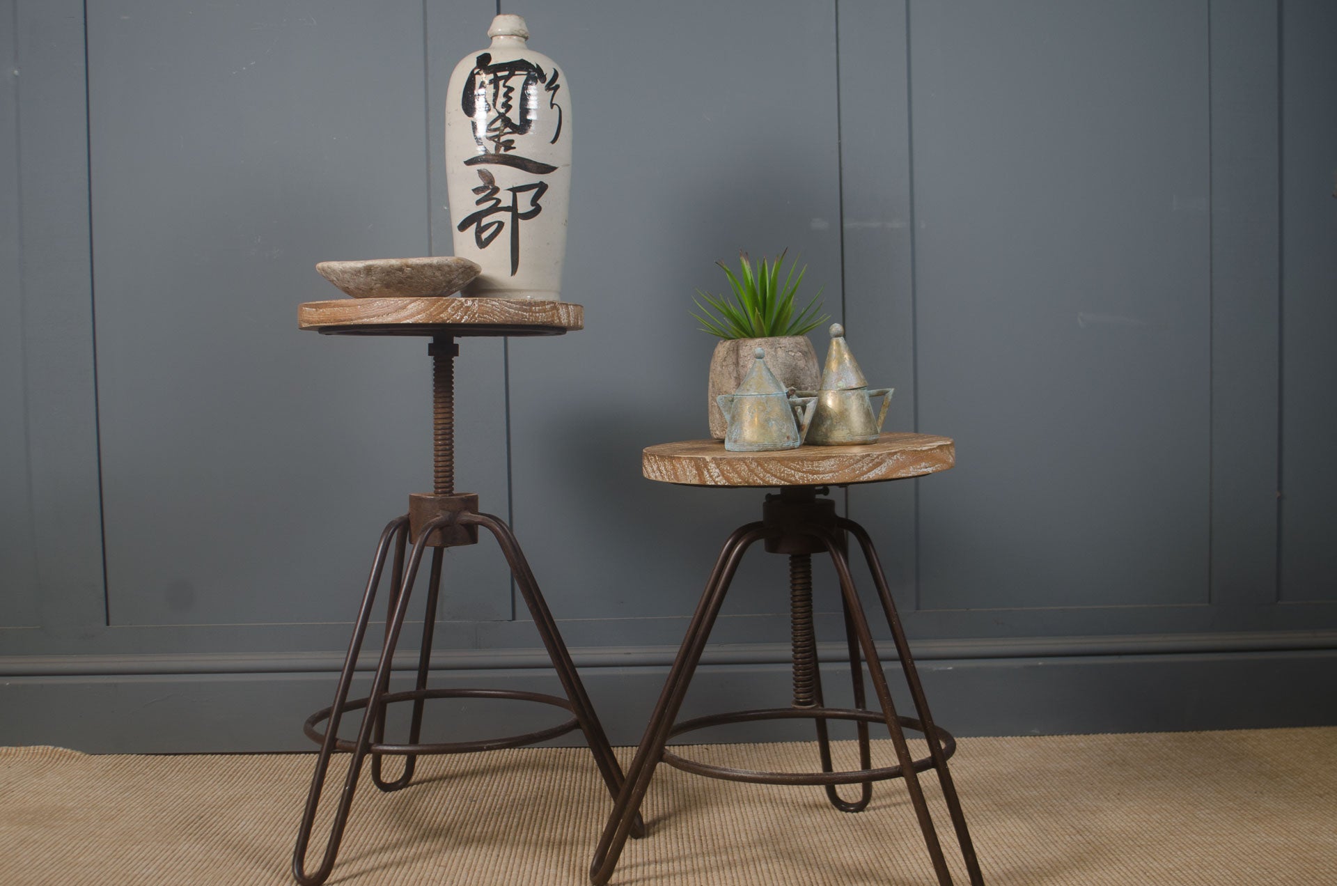 Two wooden stools with metal legs against a gray wall. adjustable height side table