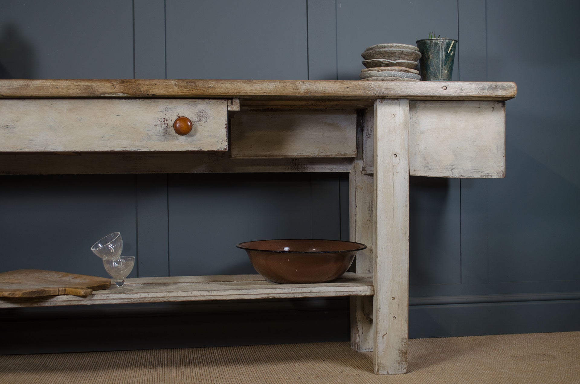 Vintage wooden workbench with rustic items against a dark blue wall.