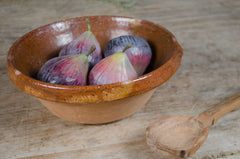 Terracotta bowl with figs on a wooden surface