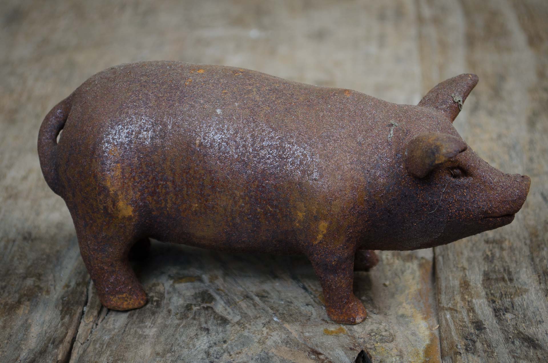 cast iron garden pig ornament stood side on, with rustic wood table