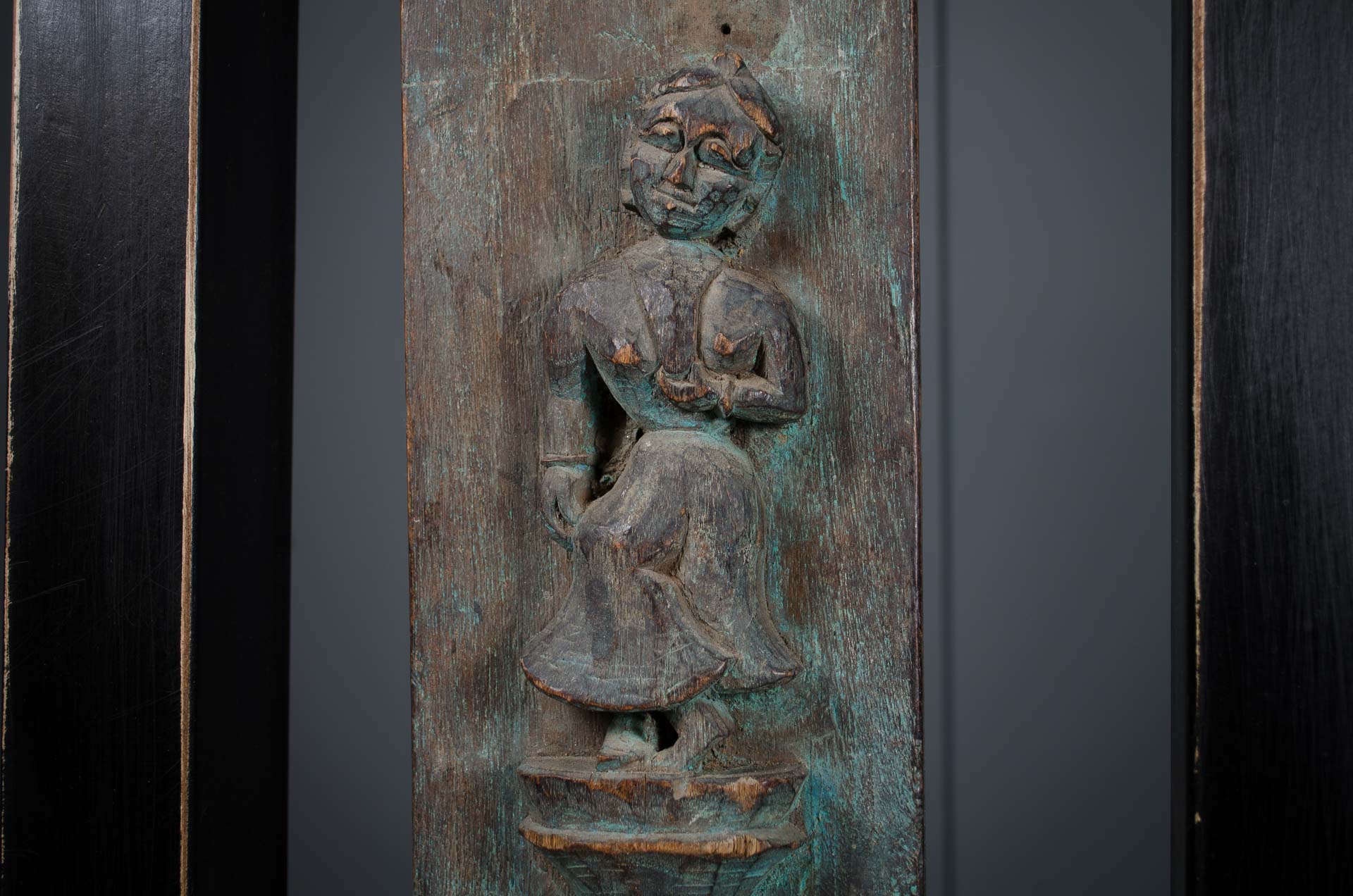 carved indian plaque with a seated figure on a dark background