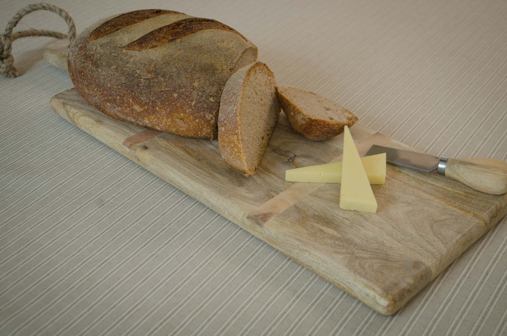 
Rustic mango wood cheese board with olives, butter and sourdough bread