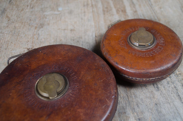 Antique leather tape measure cases with brass hardware.