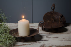 Candle in a rustic metal holder on a wooden surface with a dark background