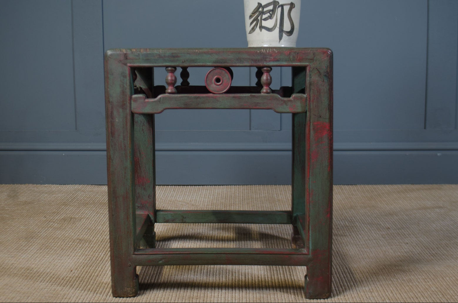 Vintage wooden table with a white bottle featuring black text on a blue wall background