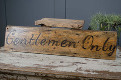 Wooden sign with 'Gentlemen Only' text on a rustic surface.