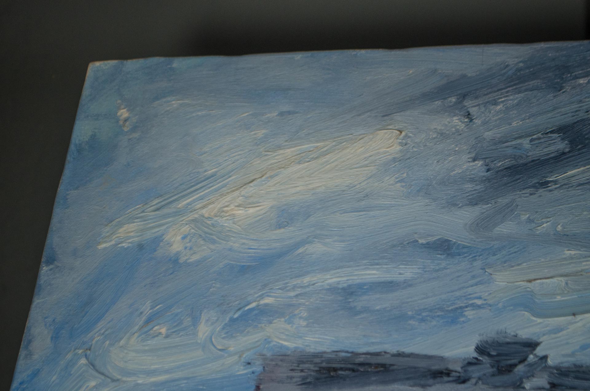 
An abstract canvas painting featuring textured brushstrokes of light blue, white, and gray paint, shown at an angle against a dark background.