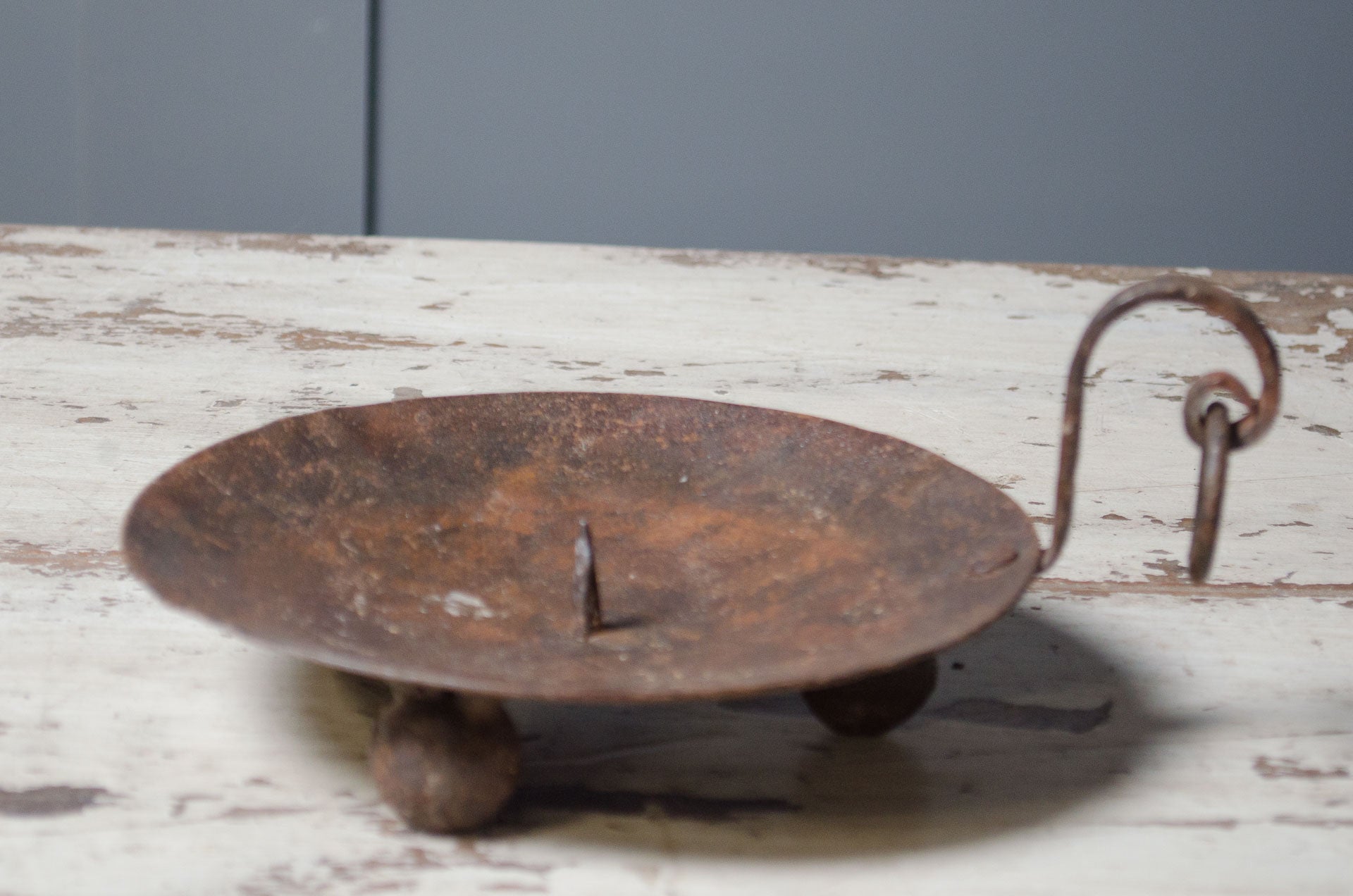 
Rust-colored metal object with a handle on a wooden surface