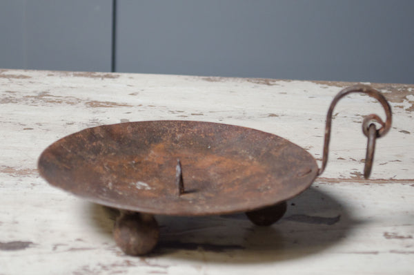 Rust-colored metal object with a handle on a wooden surface