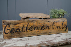 Wooden sign with 'Gentlemen Only' text on a rustic surface.