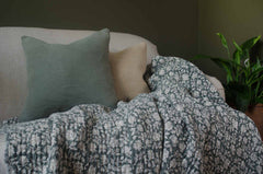 Patterned blanket draped over a sofa with two cushions in a home setting.