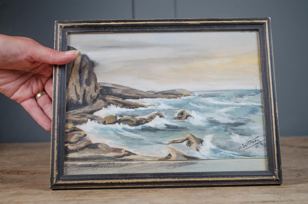 Vintage French coastal watercolour depicting waves breaking along a rocky shoreline in an ebonised and gilt painted frame.