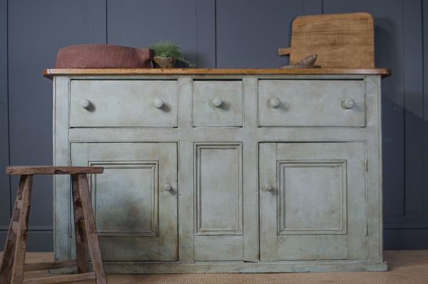 Victorian pine wooden sideboard with four drawers and two doors against a dark grey wall.