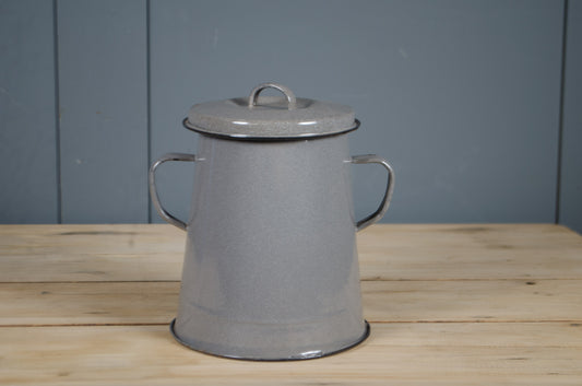 Grey enamel storage tin with lid on a wooden surface against a blue wall