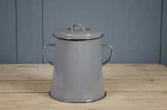 Grey enamel storage tin with lid on a wooden surface against a blue wall