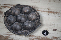 Vintage metal waffle iron on a rustic wooden surface with a number '4' tag.