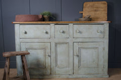 Vintage-style wooden dresser with rustic decor against a dark gray wall.