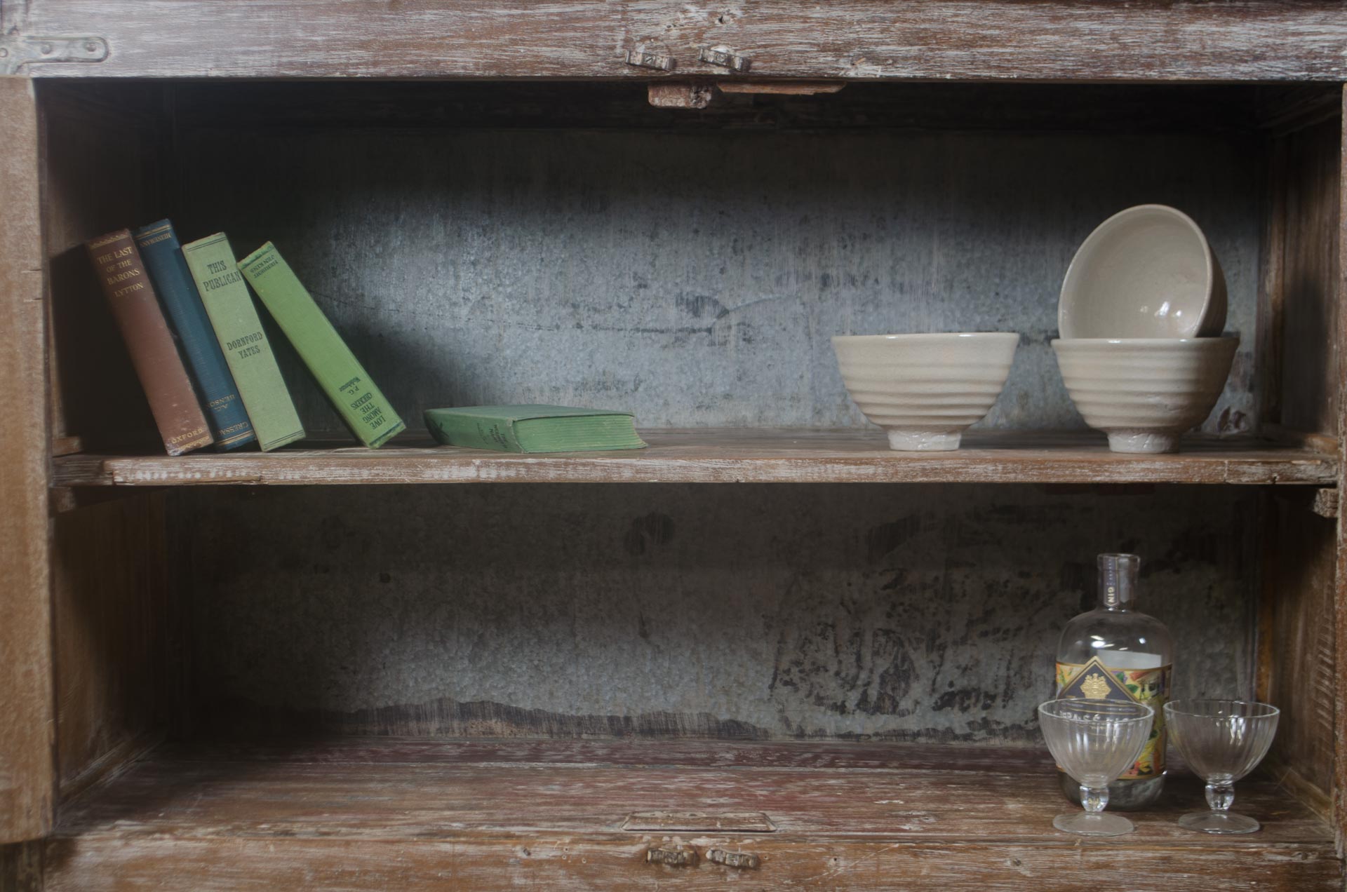 Wooden shelf with books and ceramic bowls against a textured wall.