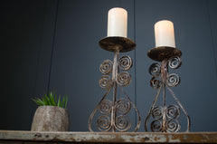 Two ornate candle holders with candles on a dark background