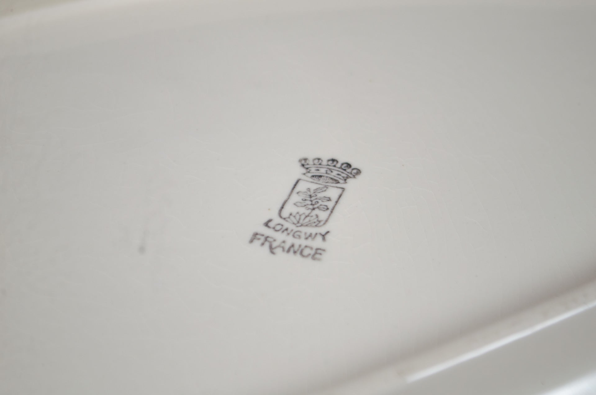 Close-up of a white dish with 'longwy France' branding on a light gray background