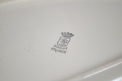 Close-up of a white dish with 'longwy France' branding on a light gray background
