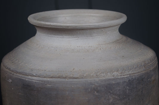 Gray ceramic jar with textured surface on a black background wabi sabi