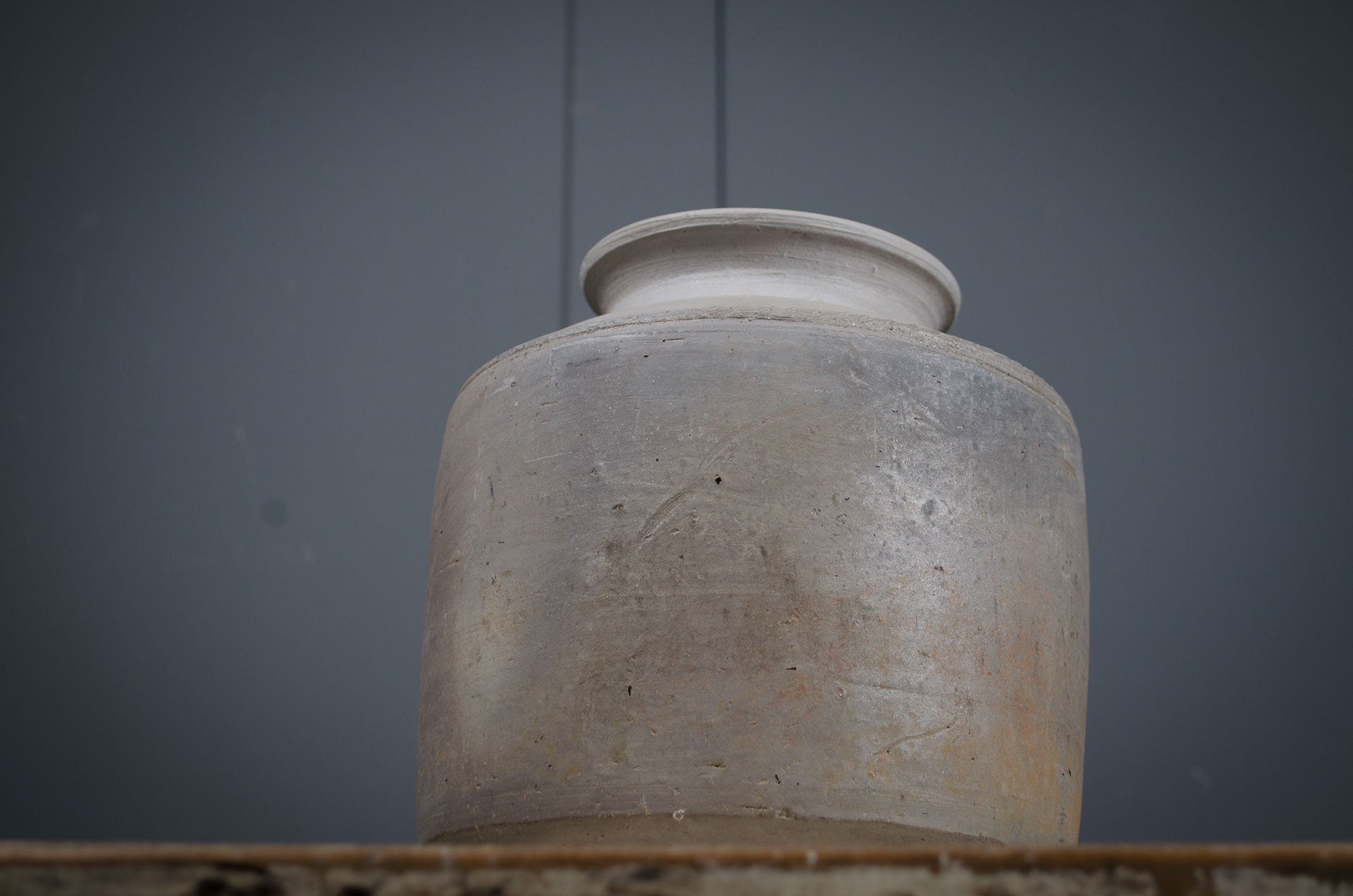 
Terracotta jar on a wooden surface with a dark gray background