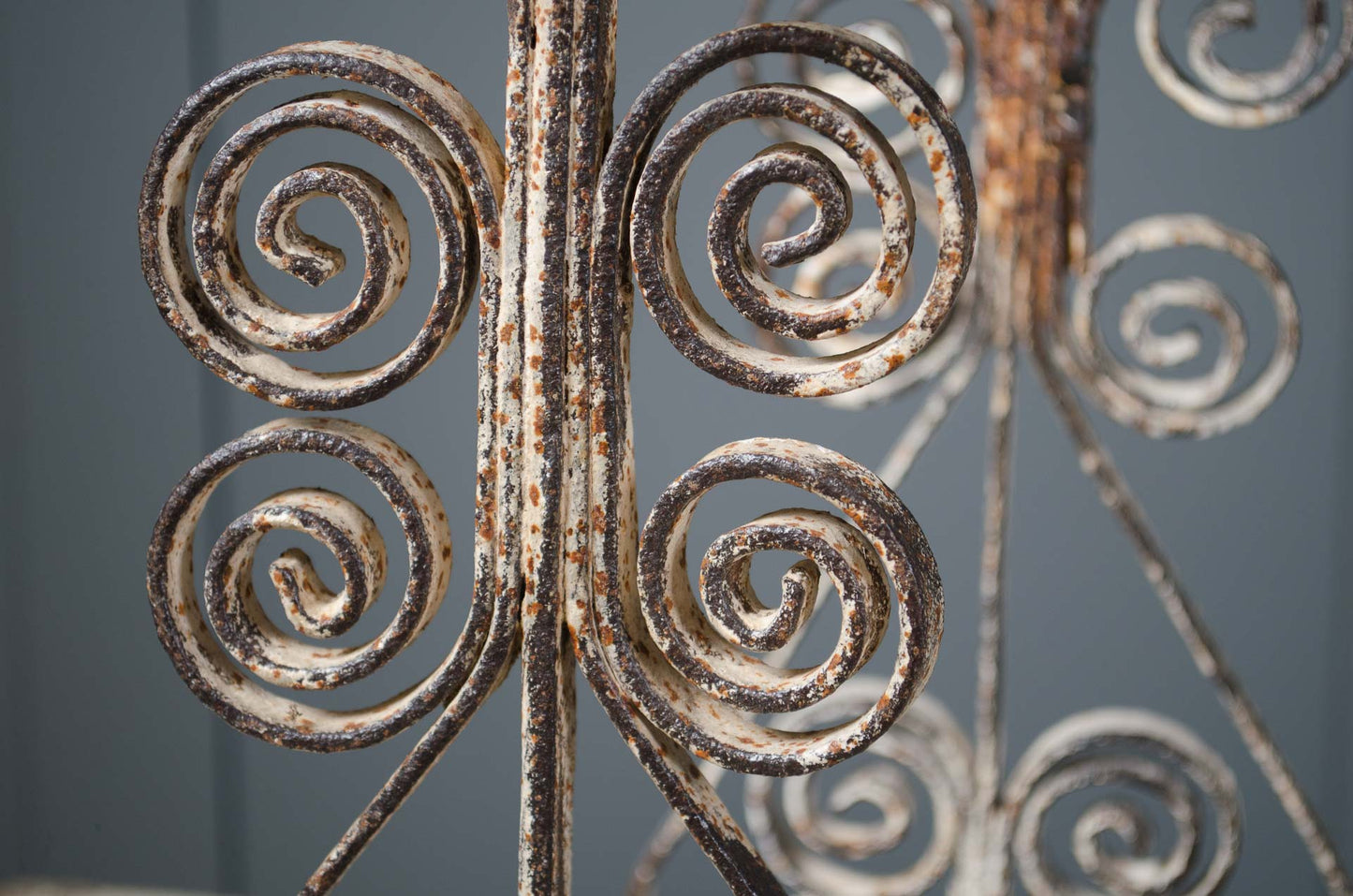 Close-up of rusted metal scrollwork against a gray background