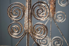 Close-up of rusted metal scrollwork against a gray background