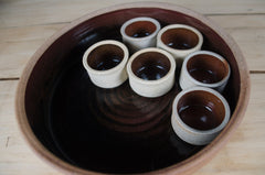 Large handmade stoneware bowl with six dipping pots featuring black and rust reactive glaze finish.