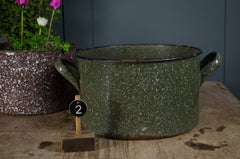 Green speckled pot on a wooden surface with a dark background