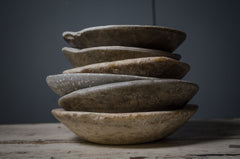 Stack of stone bowls on a wooden surface with a dark background