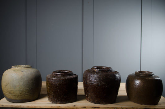 Authentic antique brown Chinese storage jars displayed together showing unique handmade forms