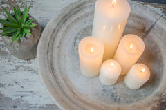 Candle holder with lit candles on a rustic wooden surface in a stone bowl