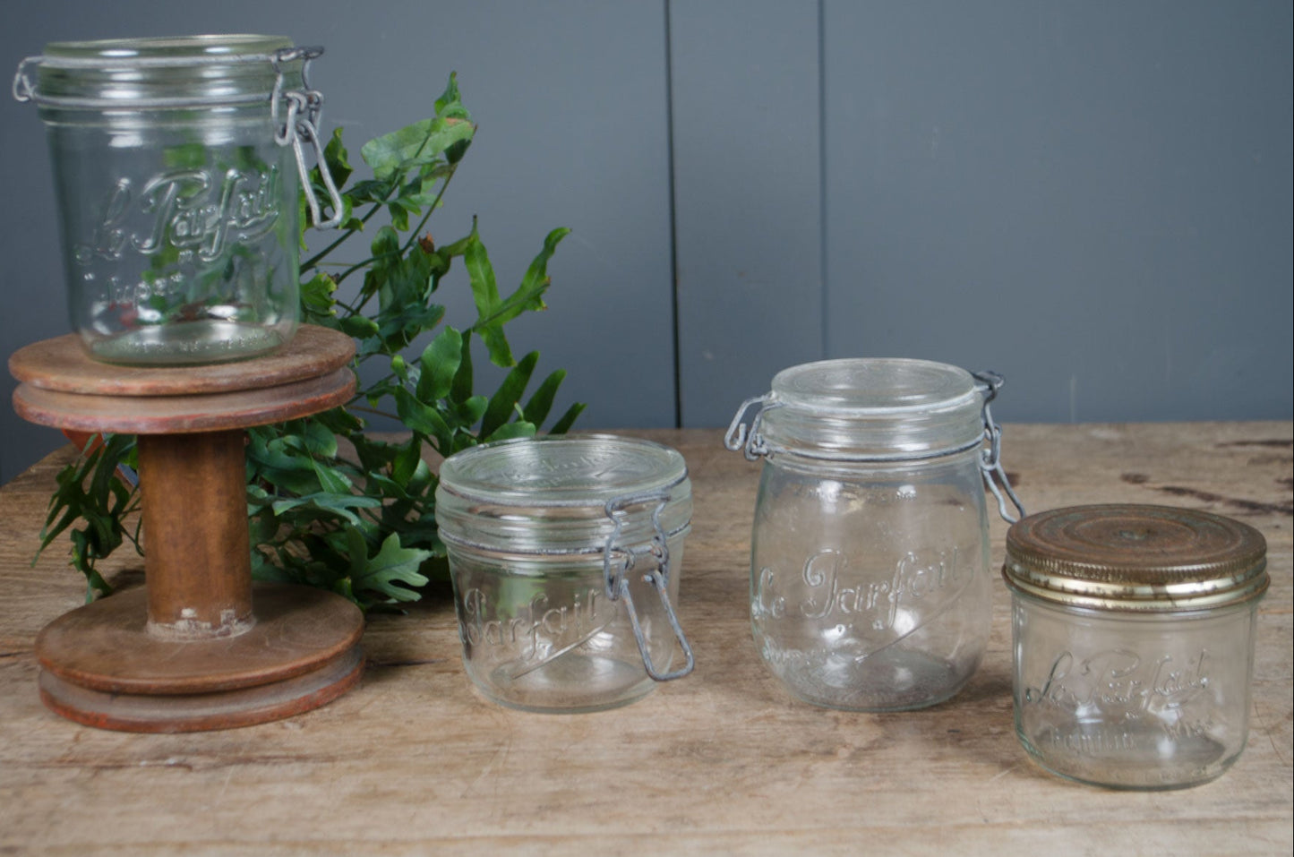 Vintage French Le Parfait glass storage jars with embossed branding and wire fastening lids in assorted sizes.