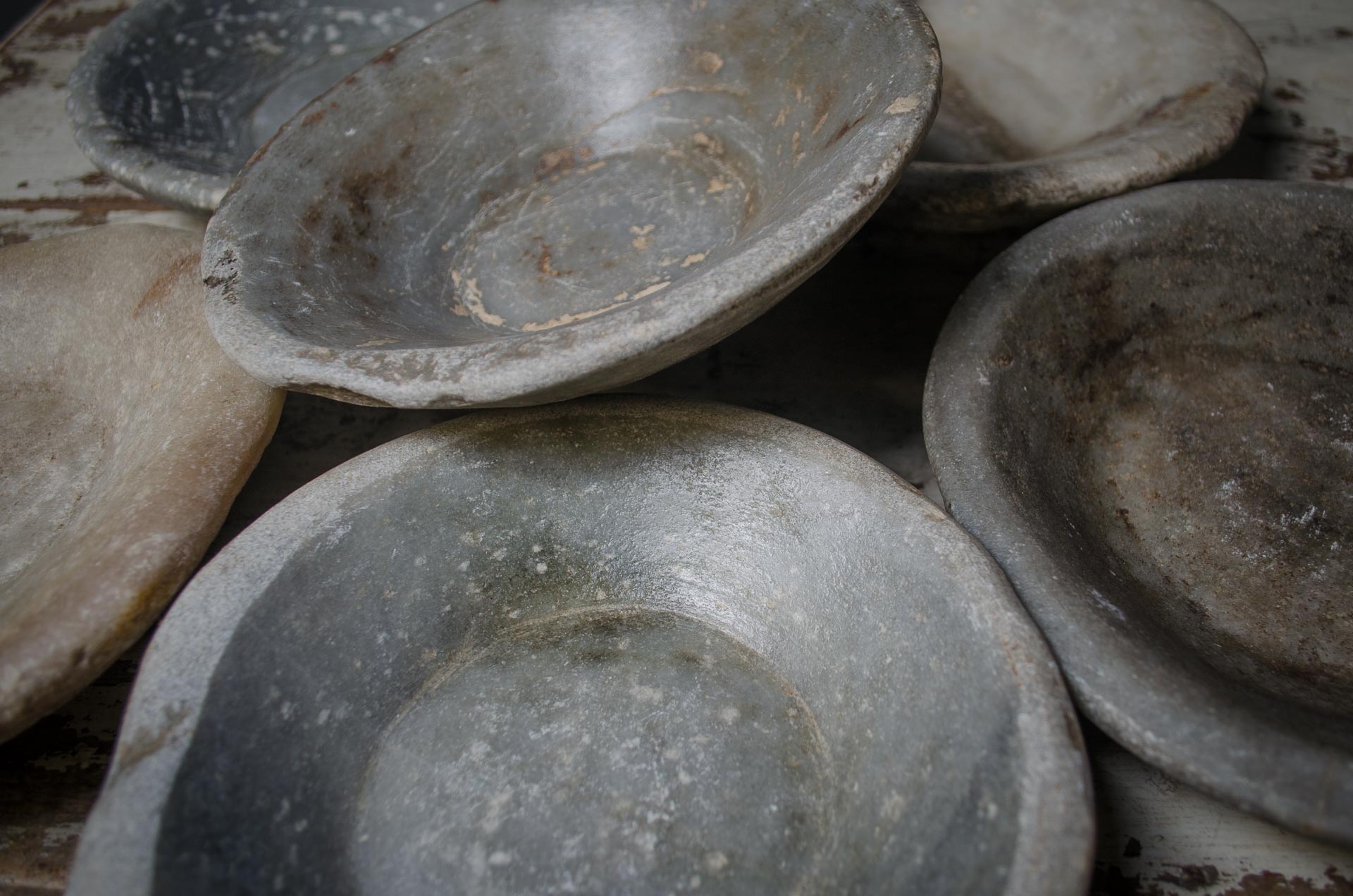 
Stack of old, worn ceramic stone bowls with a dark background on a reclaimed kitchen farmhouse table