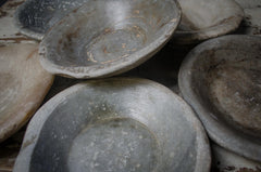 Stack of old, worn ceramic stone bowls with a dark background on a reclaimed kitchen farmhouse table