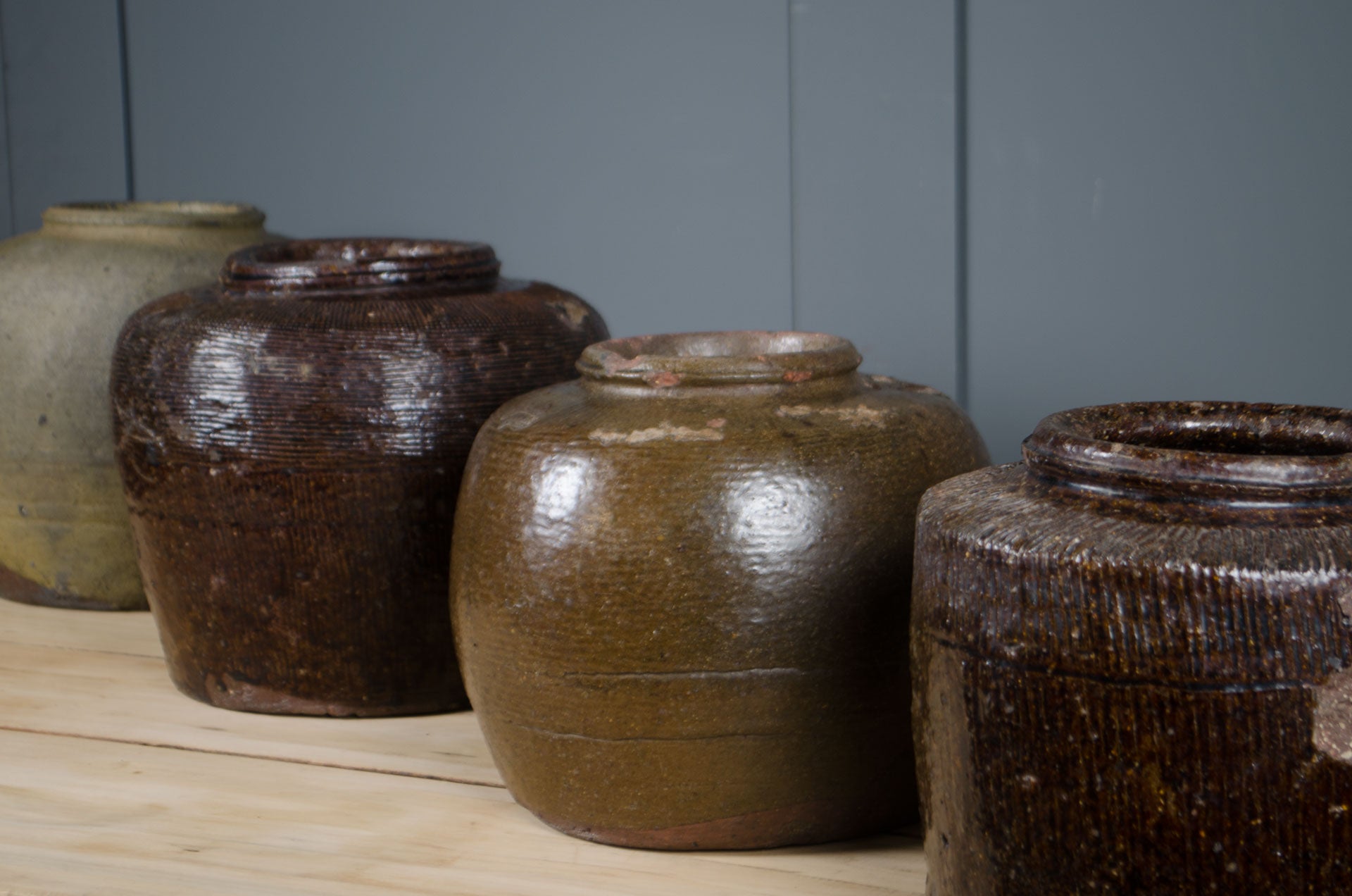 
Collection of antique Chinese preserve jars with aged brown and olive stoneware glazes.