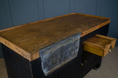 Vintage workbench with a wooden top and metal drawers against a blue wall. butchers block