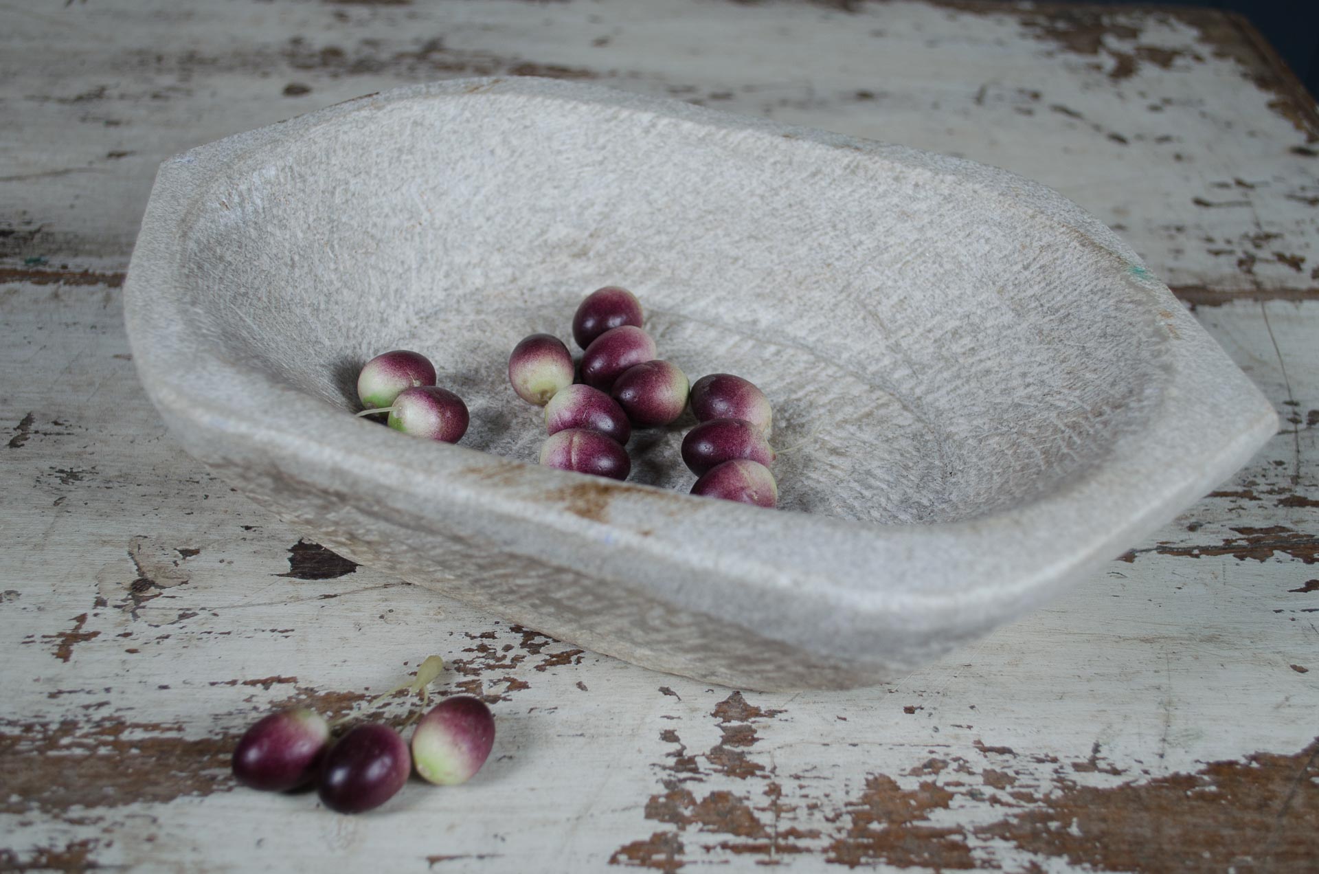 Stone mortar with purple fruits on a rustic wooden surface