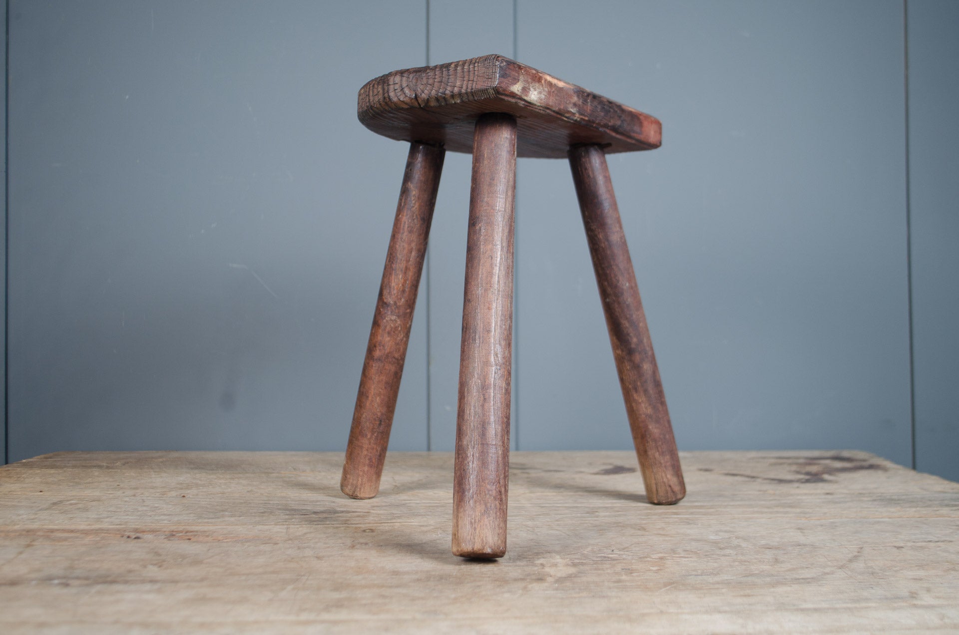 
Rustic French wooden milking stool with three legs and a weathered patina, sourced from France.