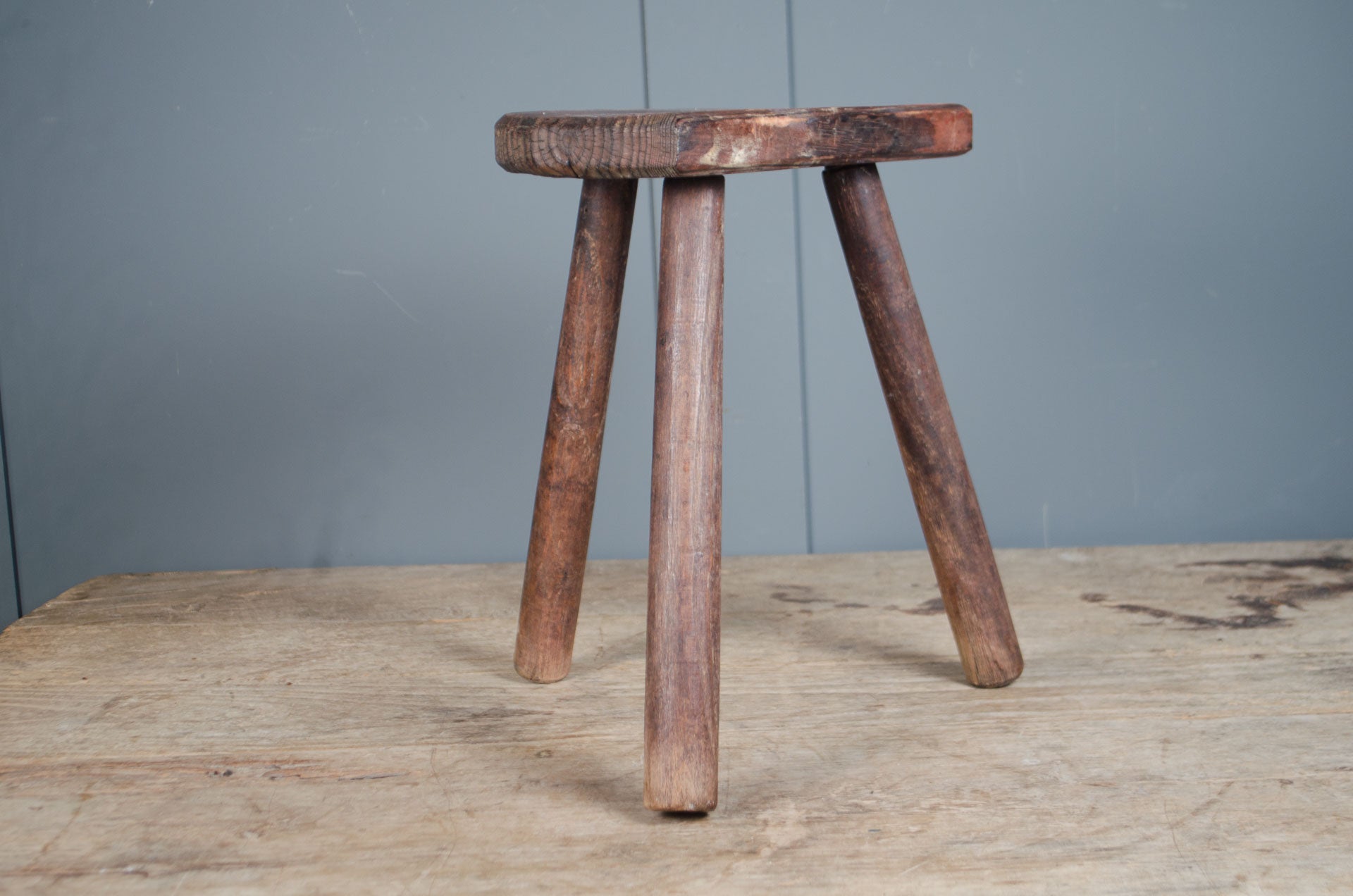 
Rustic French wooden milking stool with three legs and a weathered patina, sourced from France.