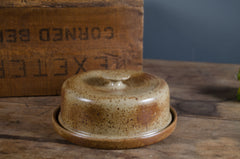 Stoneware butter dish with lid on a wooden surface with a vintage box in the background