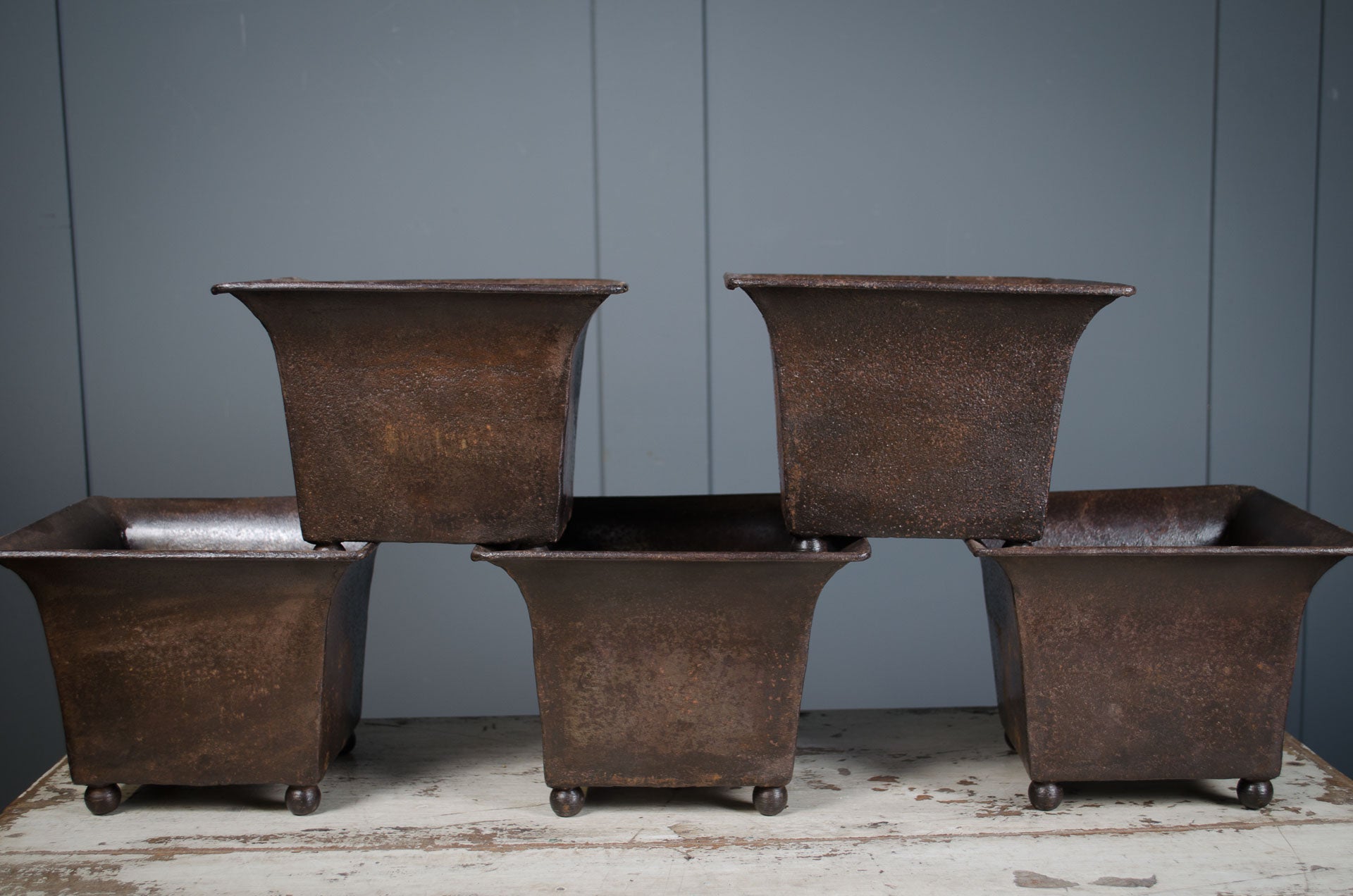 
Set of five rusted metal planters against a gray wall.