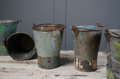 Set of rusty metal buckets on a wooden surface with a gray background