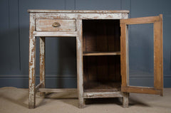 Vintage wooden side table with a distressed finish against a dark blue wall.
