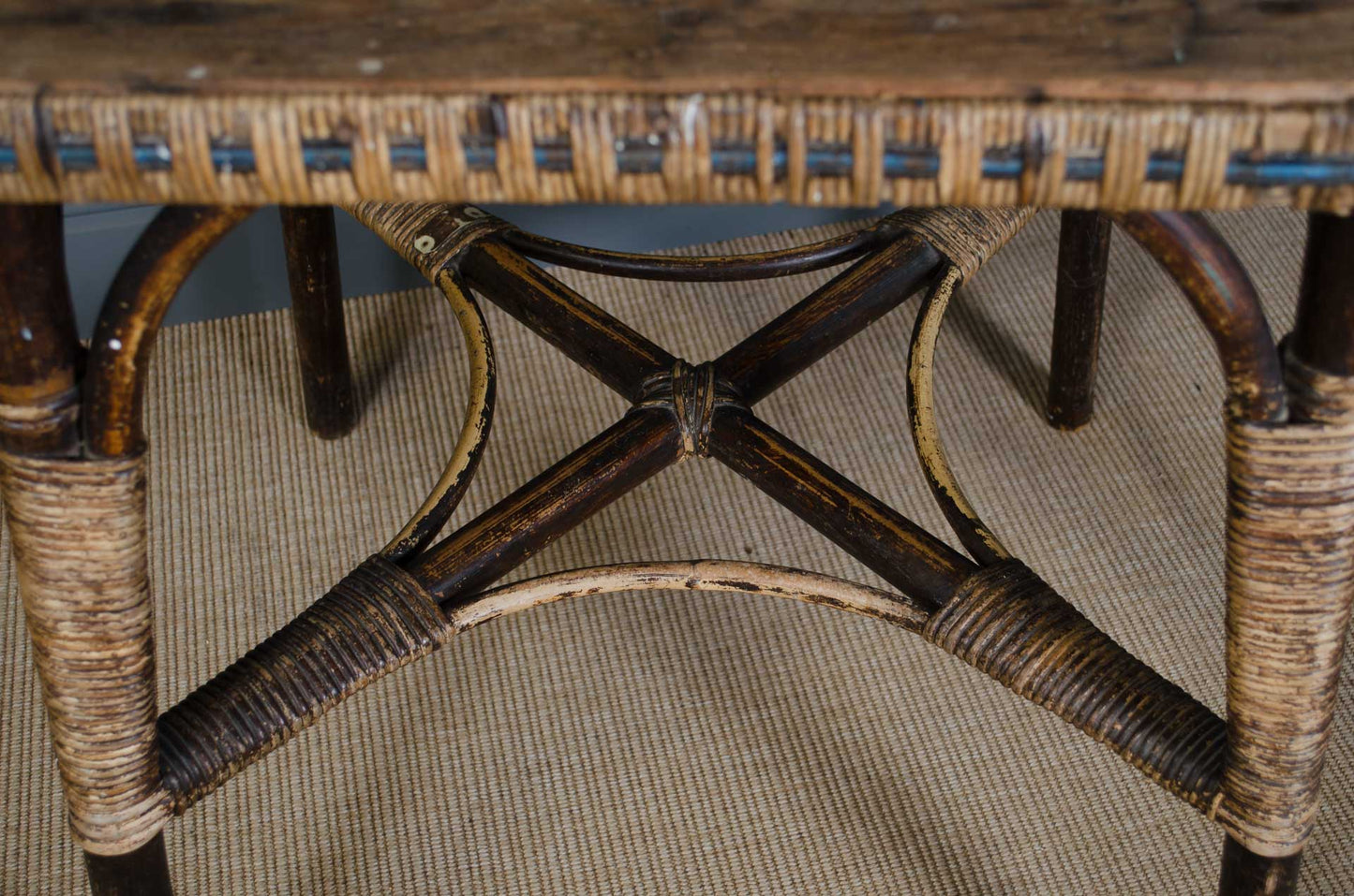 Close-up of a wicker chair with a wooden seat on a carpeted floor.