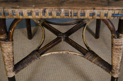 Close-up of a wicker chair with a wooden seat on a carpeted floor.