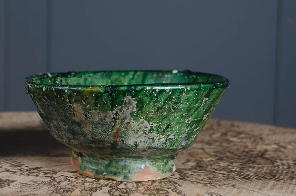 Green ceramic bowl and stone pot with plant on a textured surface against a dark background Moroccan Vintage Tamegroute